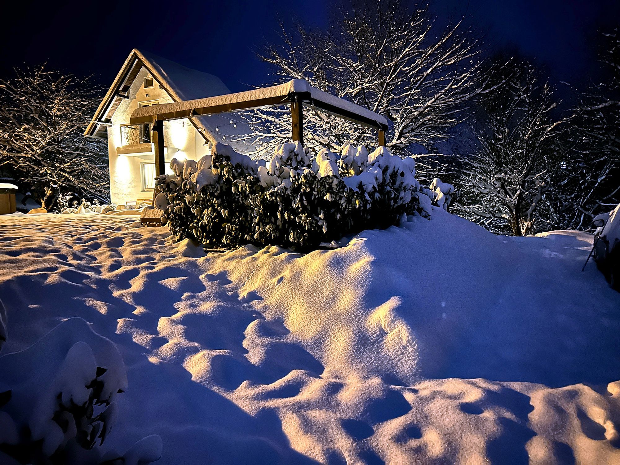 The Tri Trešnje house lit up in the snow on a winter evening